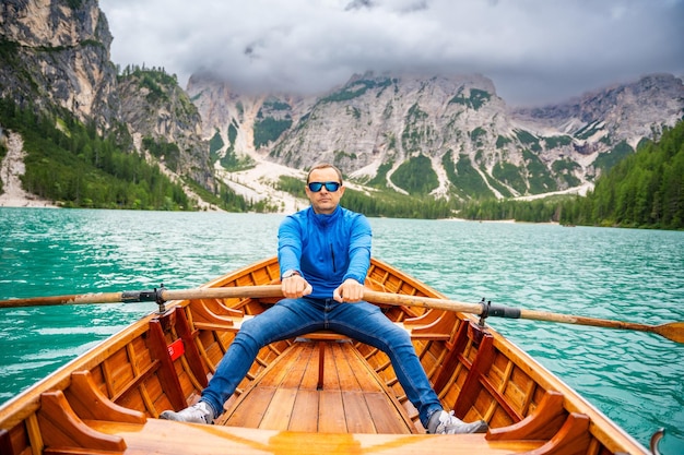 Uomo seduto in una grande barca marrone al lago di Braies in un giorno nuvoloso in Italia vacanze estive in Europa