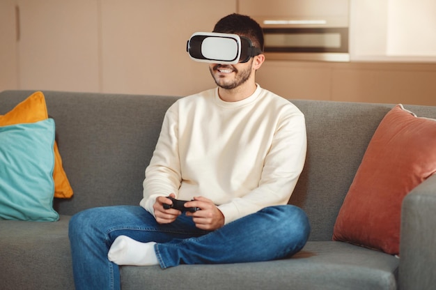 Uomo seduto sul divano con le cuffie virtuali