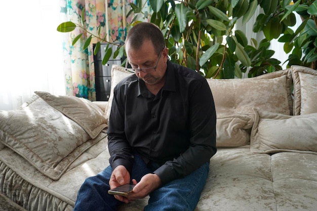 uomo seduto sul divano e guardando lo smartphone