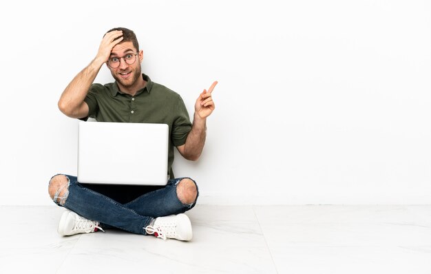 uomo seduto sul pavimento con un laptop