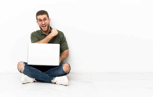 uomo seduto sul pavimento con un laptop