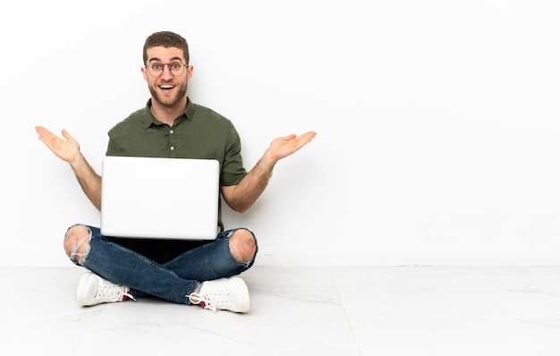 uomo seduto sul pavimento con un laptop