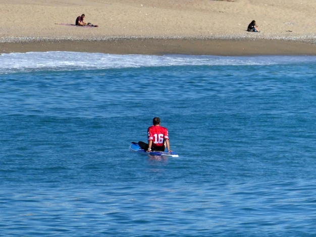 Uomo seduto sulla tavola da paddle surf in mare
