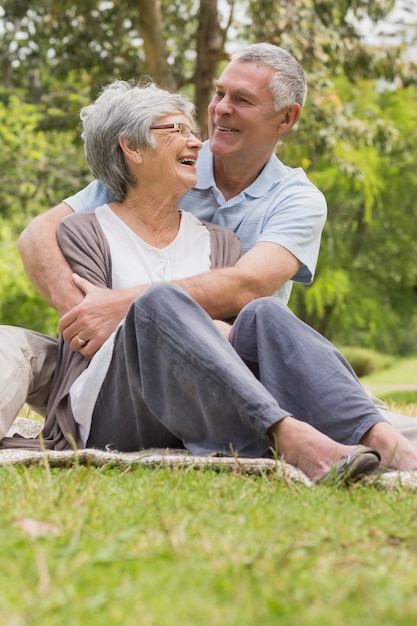 Uomo senior che abbraccia donna da dietro al parco