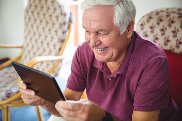 Uomo senior che per mezzo di una compressa digitale