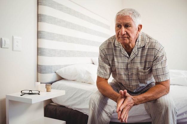 Uomo senior che si siede sul letto in camera da letto