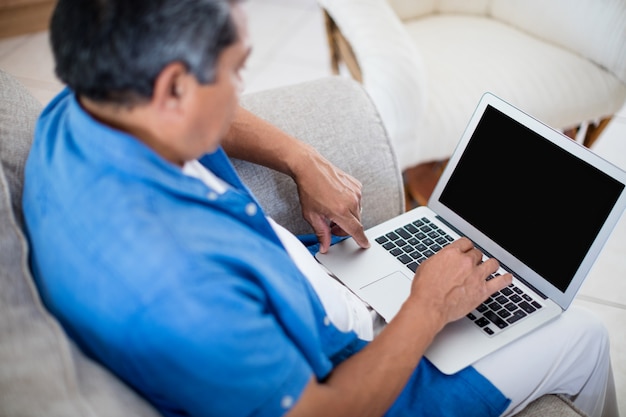 Uomo senior che utilizza computer portatile nel salone