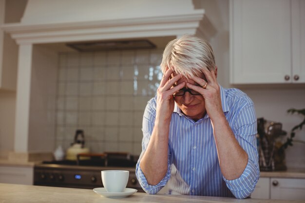 Uomo senior preoccupato che si siede con una tazza di caffè