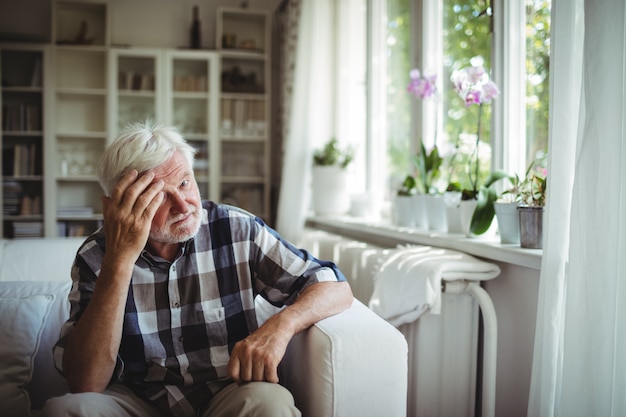 Uomo senior teso che si siede sul sofà