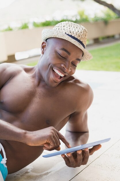 Uomo senza camicia bello che utilizza il poolside del pc del ridurre in pani