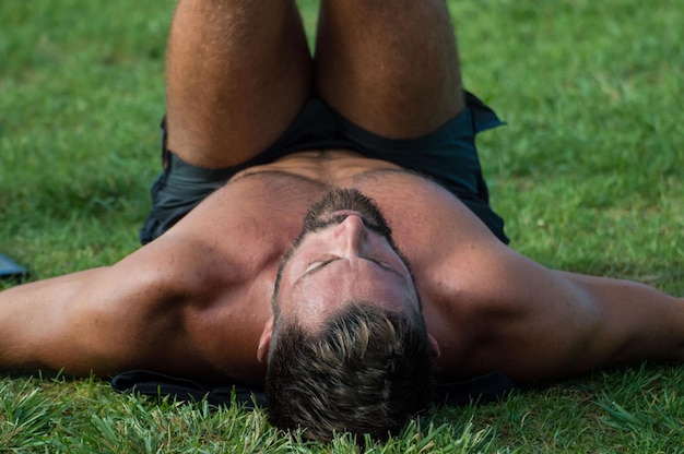 Uomo senza camicia che si esercita sull'erba al parco