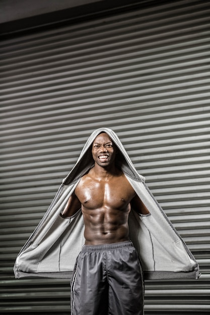 Uomo senza camicia in piedi con maglione grigio nella palestra di crossfit