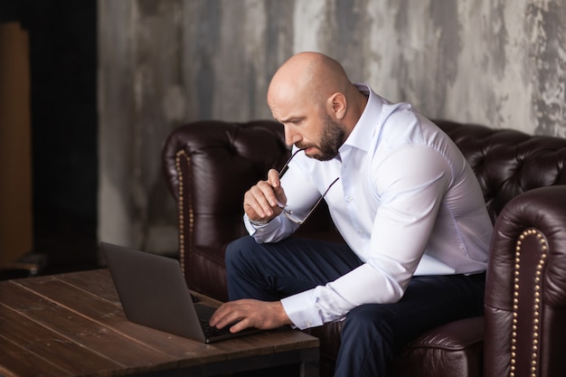 Uomo serio adulto che lavora al computer in ufficio