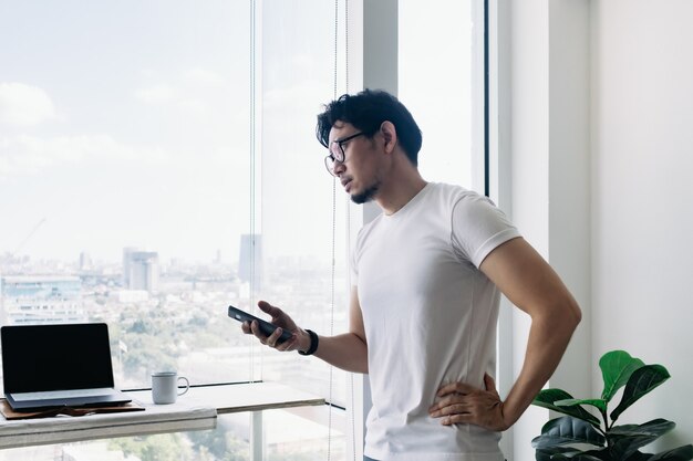 Uomo serio che lavora con computer e telefono con vista a molti piani