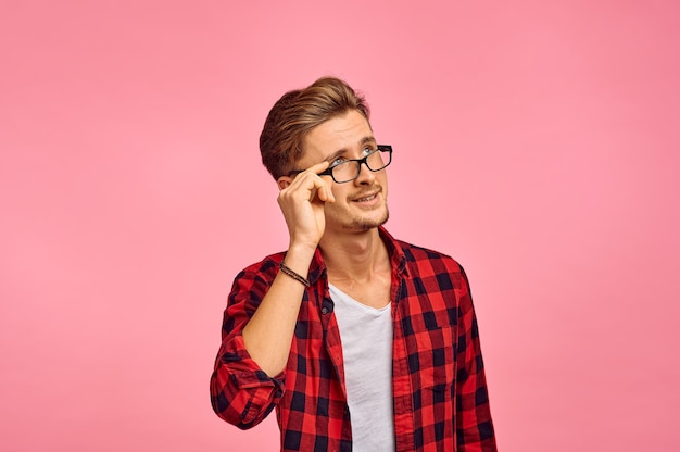 Uomo serio con gli occhiali, muro rosa, emozione. Espressione del viso, persona di sesso maschile che guarda sulla fotocamera in studio, concetto emotivo, sentimenti