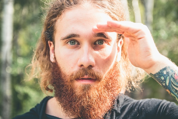 uomo serio con la barba che guarda attraverso le sue mani molto concentrato