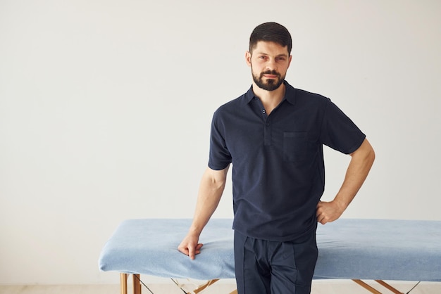 Uomo serio in camicia in piedi al chiuso su sfondo bianco