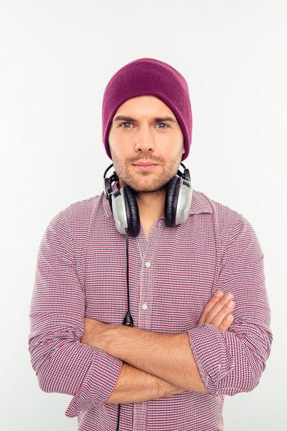 Uomo serio in cappello e cuffie con le mani incrociate