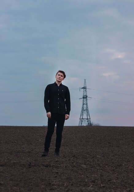 Uomo serio sul campo, vestito di nero. Tramonto rosa