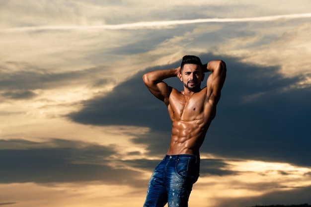 Uomo sexy con corpo muscoloso su cielo blu