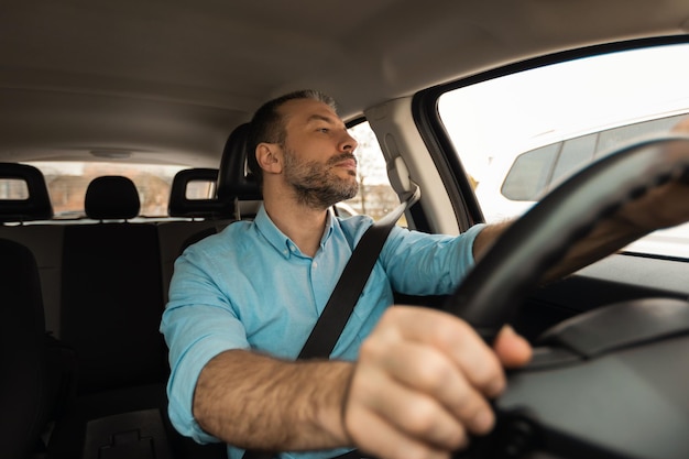 Uomo sicuro che guida la nuova automobile in città