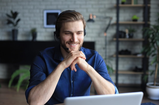 Uomo sicuro che indossa l'auricolare che parla e guarda la formazione sul webinar aziendale, ascoltando la lezione.