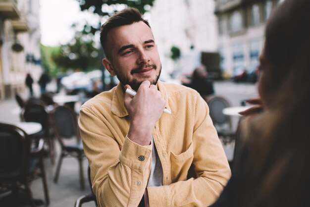 Uomo sicuro seduto al bar e guardando una persona anonima