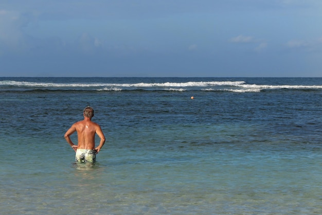 Uomo solitario sul mare tropicale sotto il cielo blu