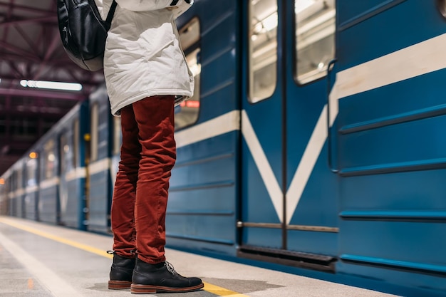 Uomo solo che aspetta mentre il treno della metropolitana apre la porta Bel maschio ben vestito con stivali neri