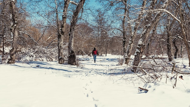 Uomo solo che cammina sulla neve nella foresta invernale