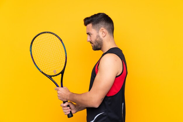 Uomo sopra giocare a tennis muro giallo isolato