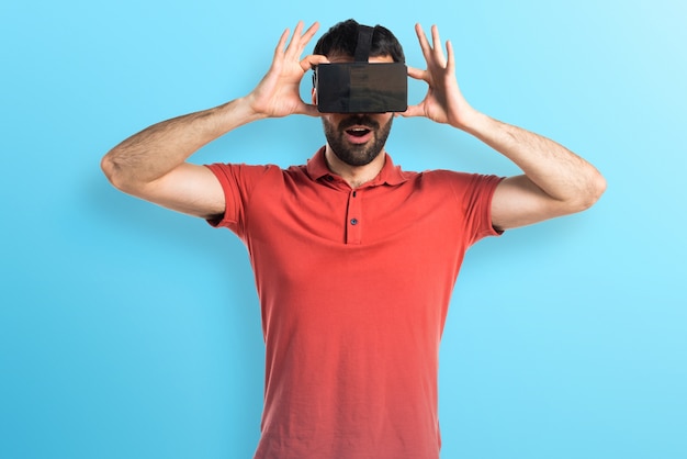 Uomo sorpreso utilizzando vetri VR su sfondo colorato