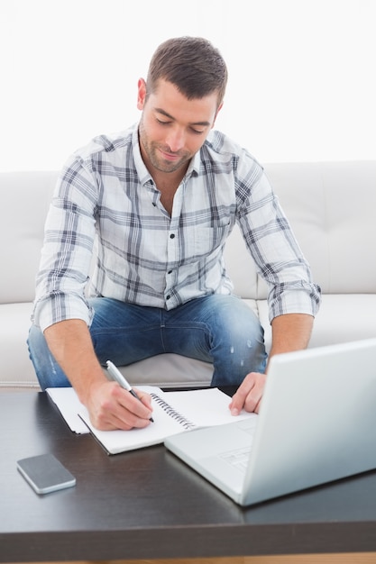 Uomo sorridente a casa su un computer portatile