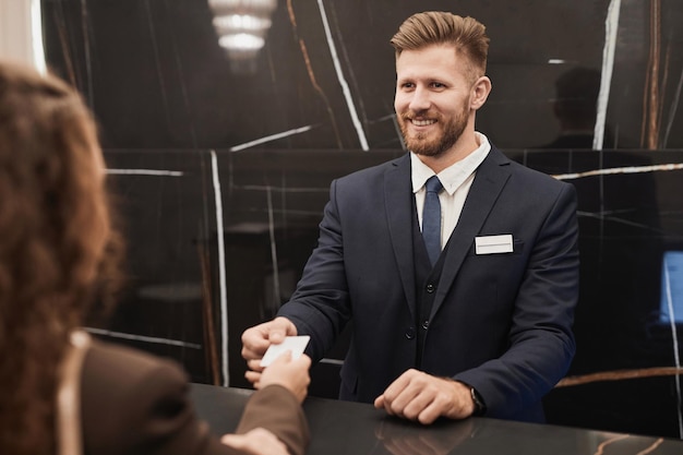 Uomo sorridente alla reception dell'hotel che accoglie gli ospiti