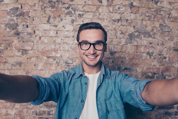 Uomo sorridente allegro bello in vetri che fanno selfie