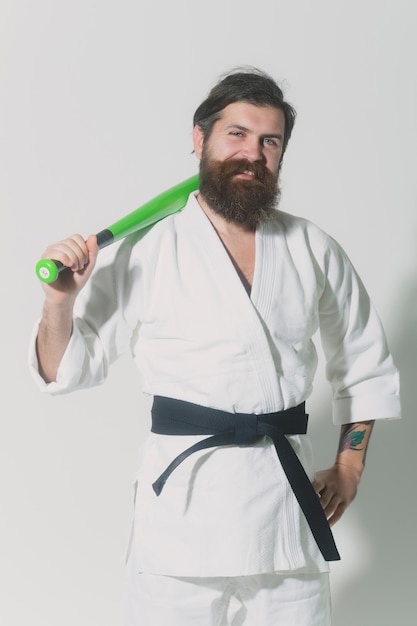 Uomo sorridente barbuto di karate in kimono con mazza da baseball verde