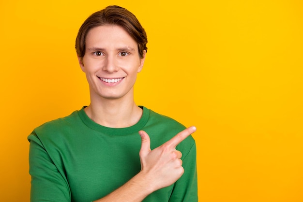 Uomo sorridente bello che indica via lo spazio vuoto giallo backgroundisolated shopping vendita