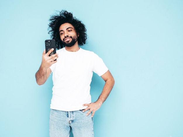 Uomo sorridente bello dei pantaloni a vita bassa che posa nello studio