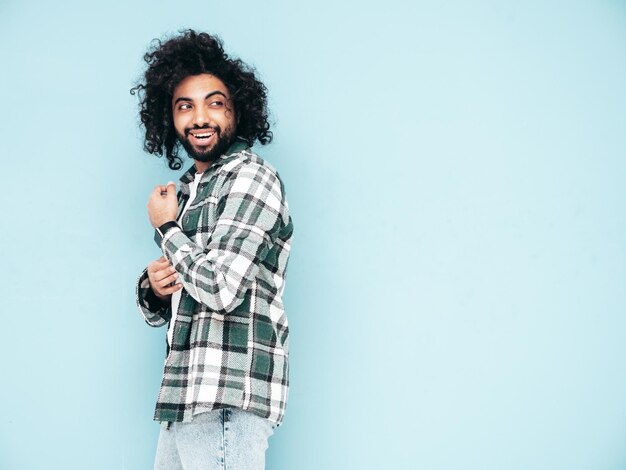 Uomo sorridente bello dei pantaloni a vita bassa che posa nello studio