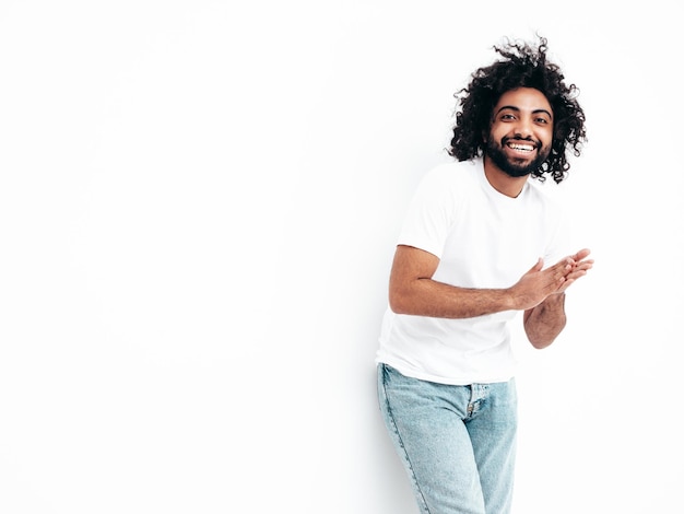 Uomo sorridente bello dei pantaloni a vita bassa che posa nello studio