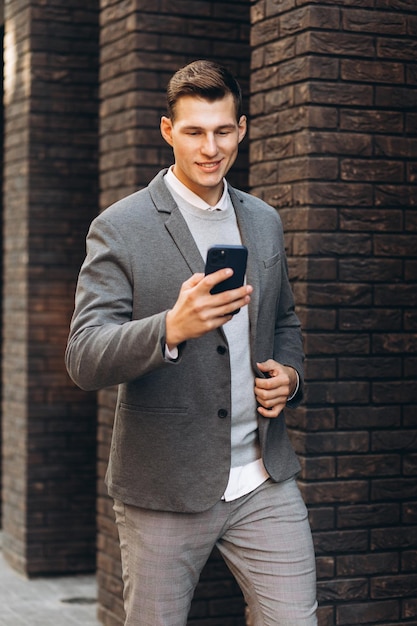 Uomo sorridente bello moderno che cammina per strada e parla al telefono