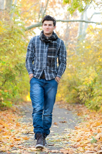 Uomo sorridente che cammina nella sosta di autunno.