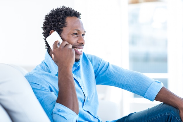 Uomo sorridente che comunica sopra il telefono mentre sedendosi