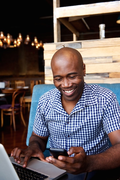 Uomo sorridente che esamina il telefono cellulare