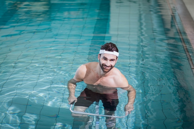 Uomo sorridente che fa bici subacquea in piscina