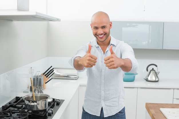 Uomo sorridente che gesturing i pollici su in cucina