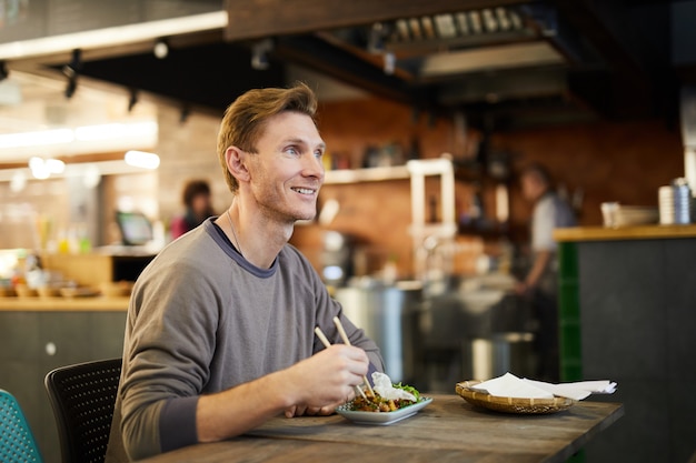 Uomo sorridente che gode del cibo asiatico