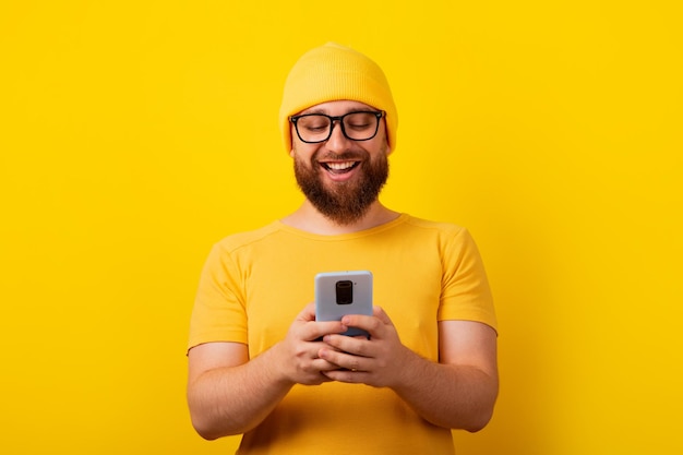 Uomo sorridente che guarda il telefono su sfondo giallo