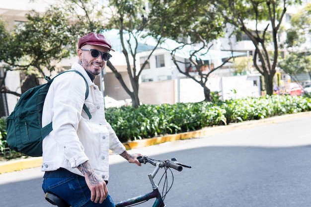 Uomo sorridente che guarda l'obbiettivo facendo una sosta durante il suo giro in bicicletta in città