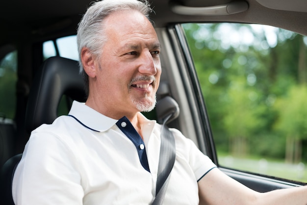 Uomo sorridente che guida la sua auto